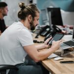 man holding turned-on iPad in front of turned-off MacBook Air